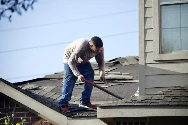 man applying sealant evenly to install new shingles
