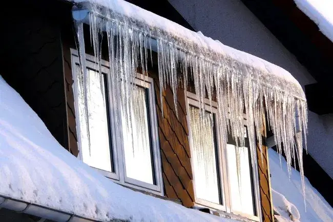 ice dam in roof blocking access to downspouts
