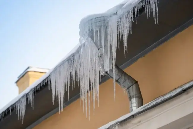 ice dam in roof blocking access to downspouts