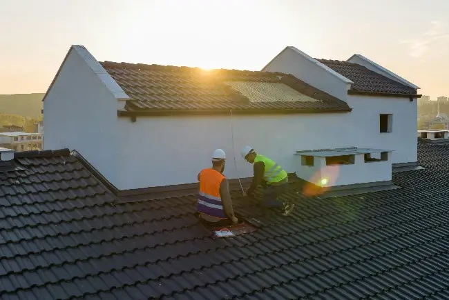 two roofers installing clay tiles on a roof