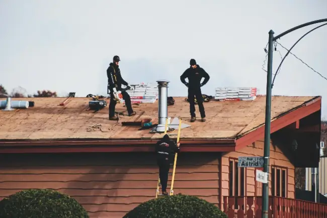 a couple of men standing on top of a roof