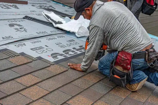 Professional roofing contractor installing asphalt shingles during a roof replacement.webp