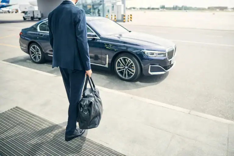 Traveler with a bag walking to a car waiting at the airport curb