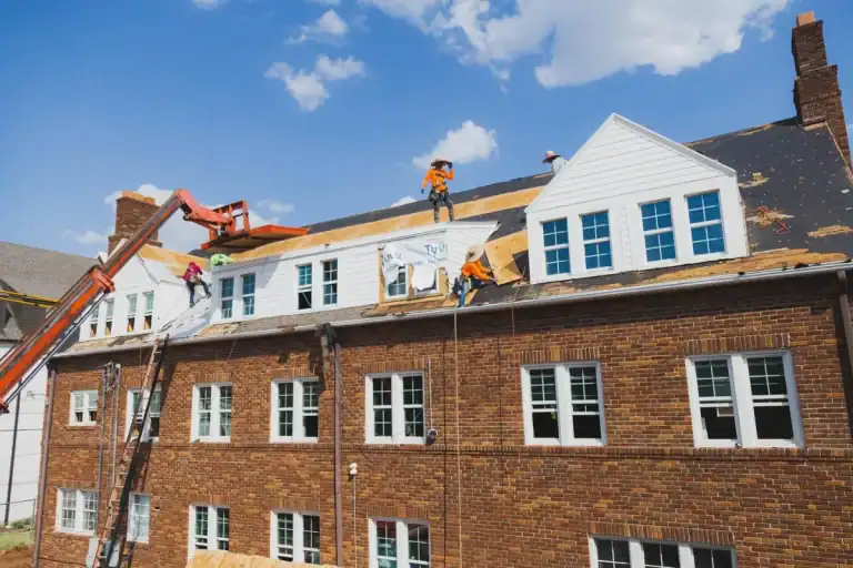Maupin Roofing & Construction crew working on the roof of a three-story brick building with a lift