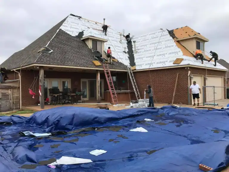Roofing crew tearing off old shingles on a brick home