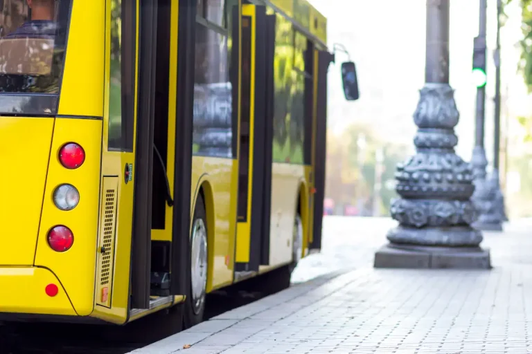 Yellow city bus with its doors open at a curbside bus stop