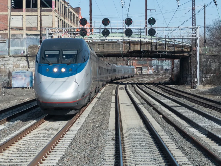 Passenger train arriving at a station under a rail bridge