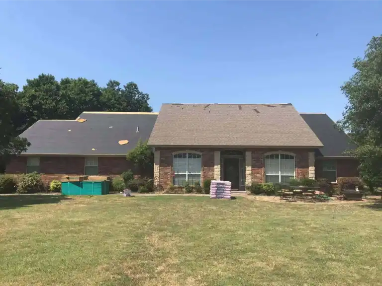 Completed roof replacement on a brick ranch home with a wide front lawn