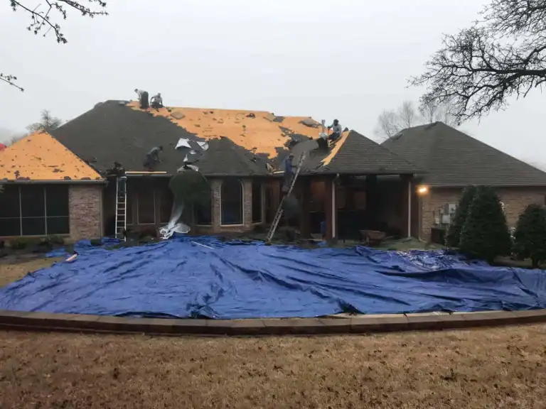 Tarps protecting the yard while a crew reroofs a brick home