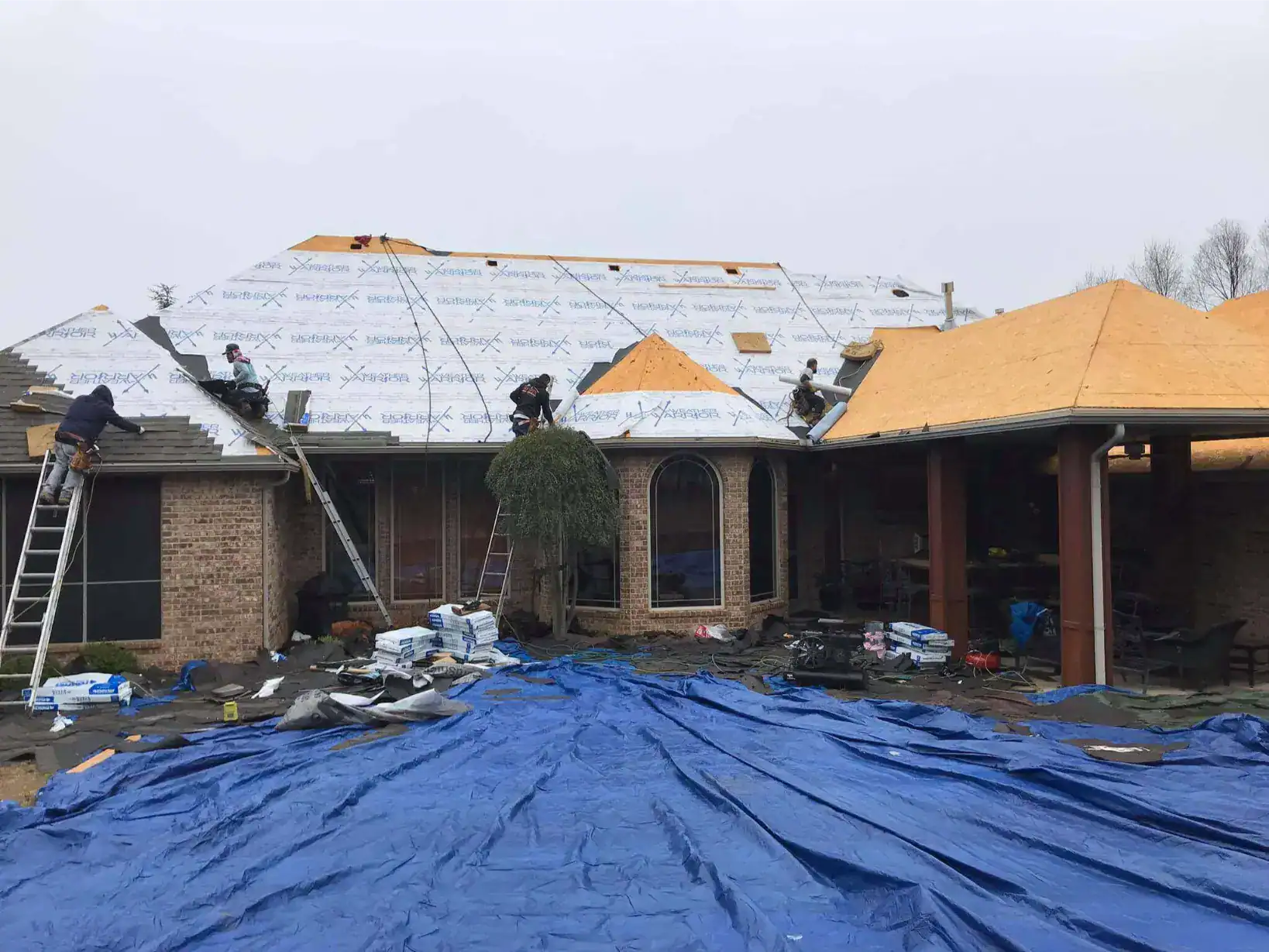 Crew installing shingles over underlayment on a brick home